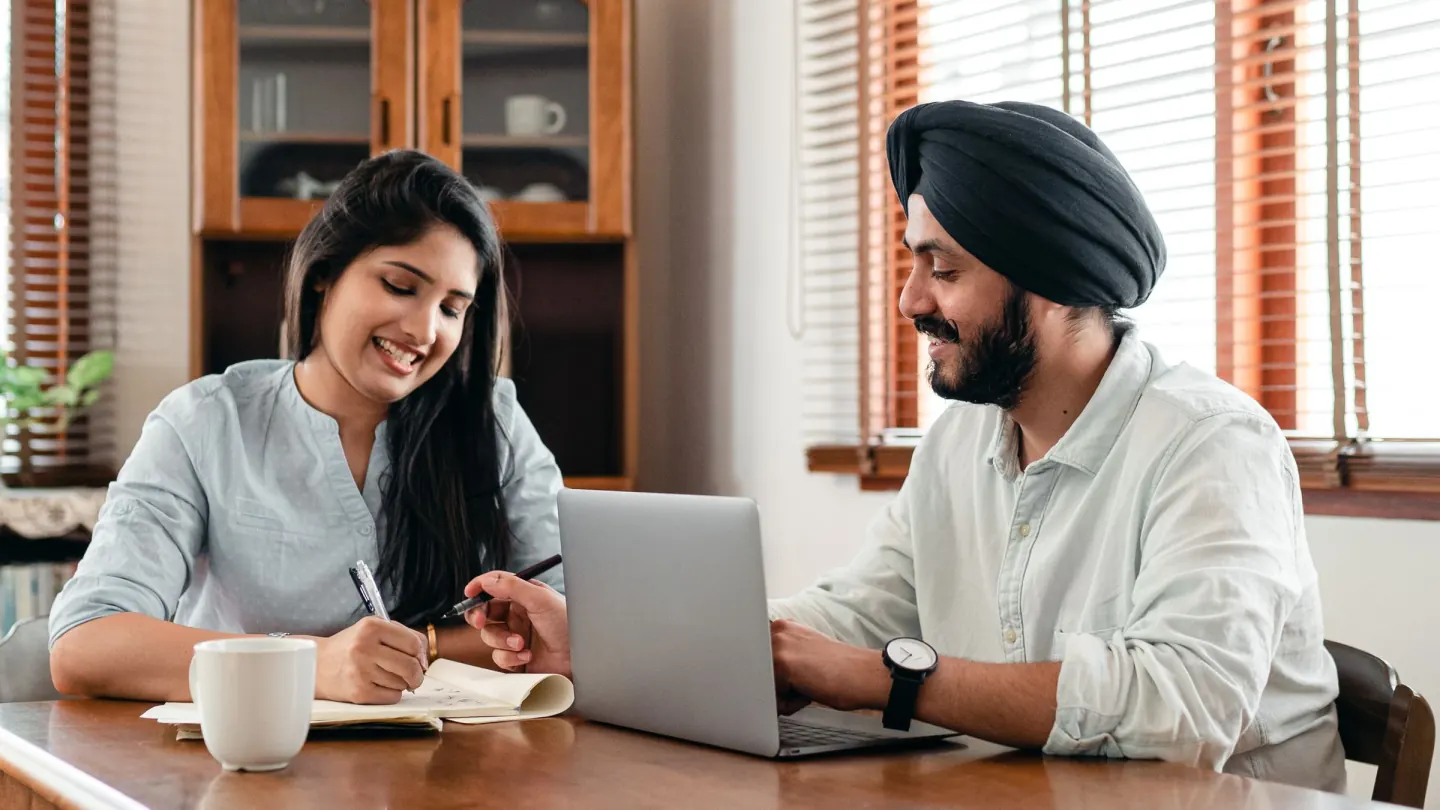 Two colleagues going through project notes together beside a laptop